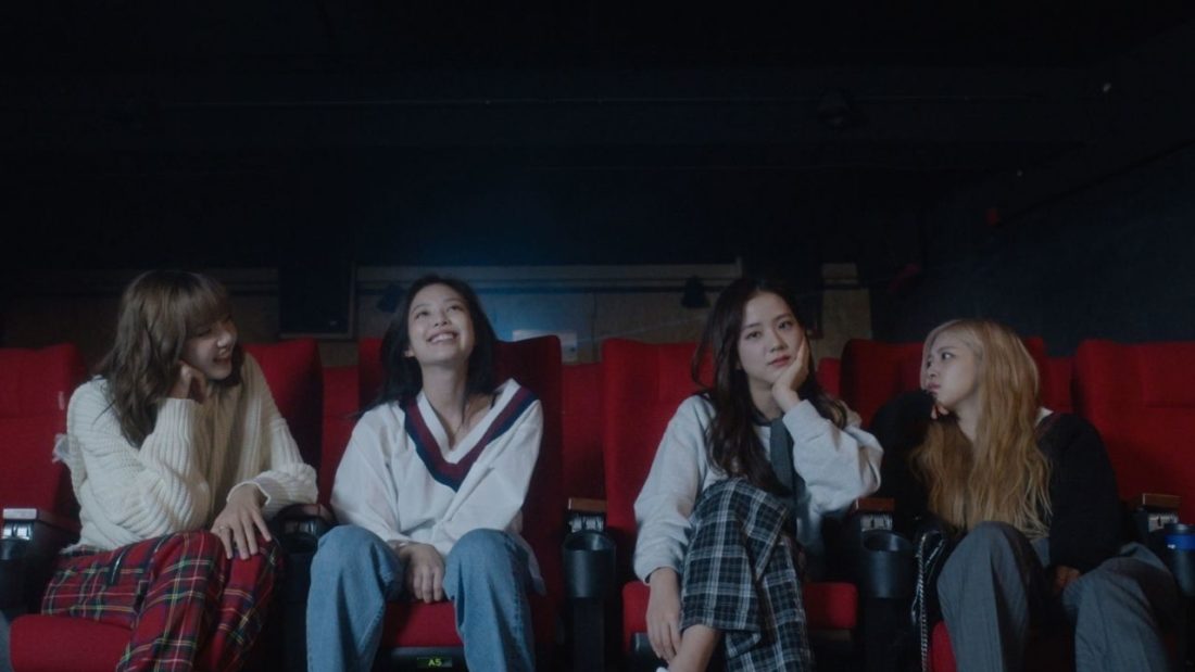 The 4 members of Blackpink sitting in a movie theatre.