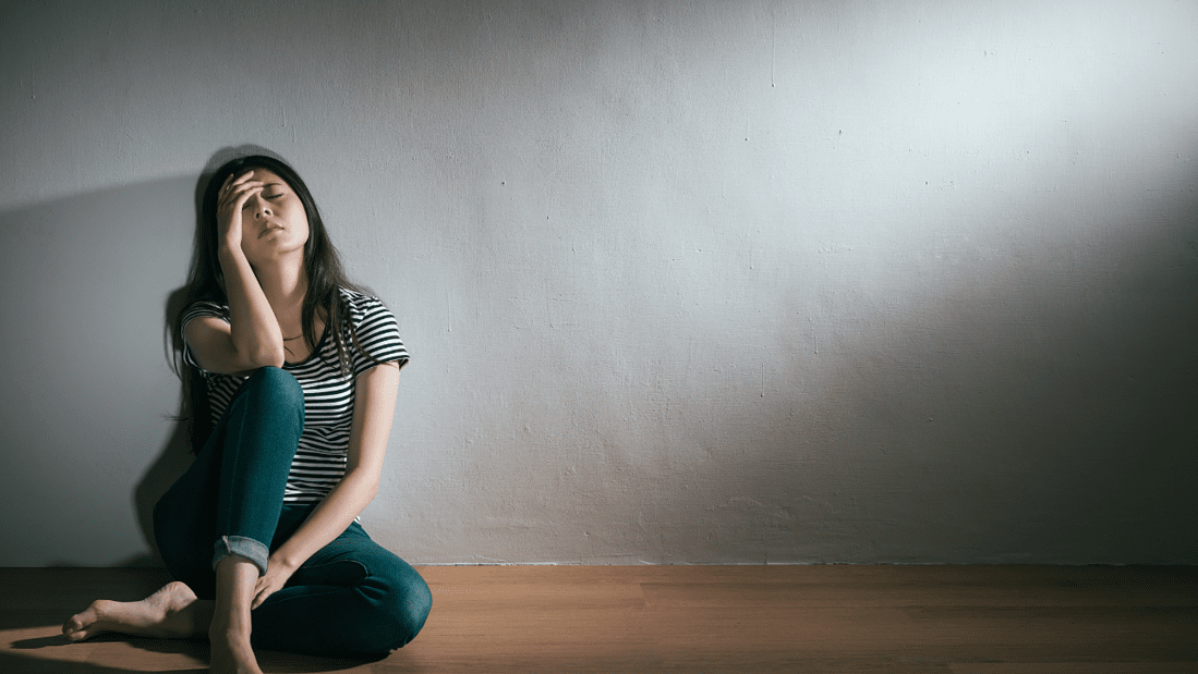 Overwhelmed woman sitting on the floor and leaning against a wall