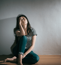 Overwhelmed woman sitting on the floor and leaning against a wall