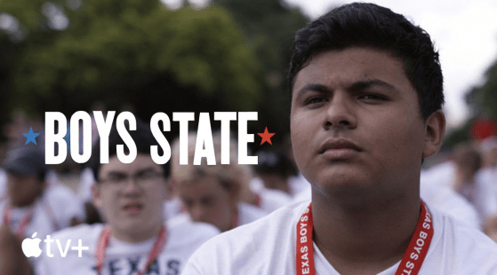 A close-up of a young man with a serious expression, wearing a red lanyard that reads "Texas Boys State." He is part of a group of similarly dressed individuals, blurred in the background. Text on the image reads "Boys State: Living In It" with a star on each side and the Apple TV+ logo.