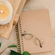 Desk with journal, eyeglasses, plant, and candle