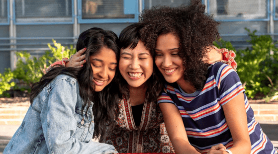 Photo of three characters from TV show Never Have I Ever sitting outside: Devi, Eleanor, and Fabiola.