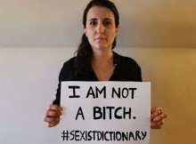 A woman holding a sign saying, "I am not a bitch. Hashtag Sexist Dictionary"