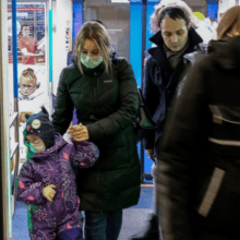 Woman walking with a child, both wearing masks