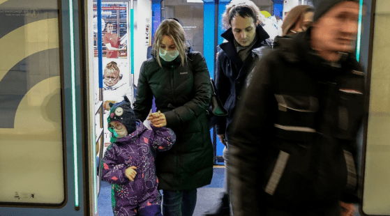 Woman walking with a child, both wearing masks