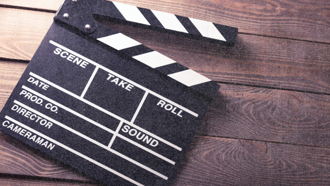 A close-up of a traditional movie clapperboard resting on a wooden surface.