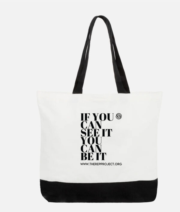 Introducing the "IF YOU CAN SEE IT TOTE": A stylish white tote bag with elegant black handles and a sturdy black bottom. It proudly displays the inspiring message "IF YOU CAN SEE IT YOU CAN BE IT" along with "WWW.THEREPPROJECT.ORG" in bold black lettering. As part of the #RespectHerGame Totes collection, this bag seamlessly combines fashion with empowerment.